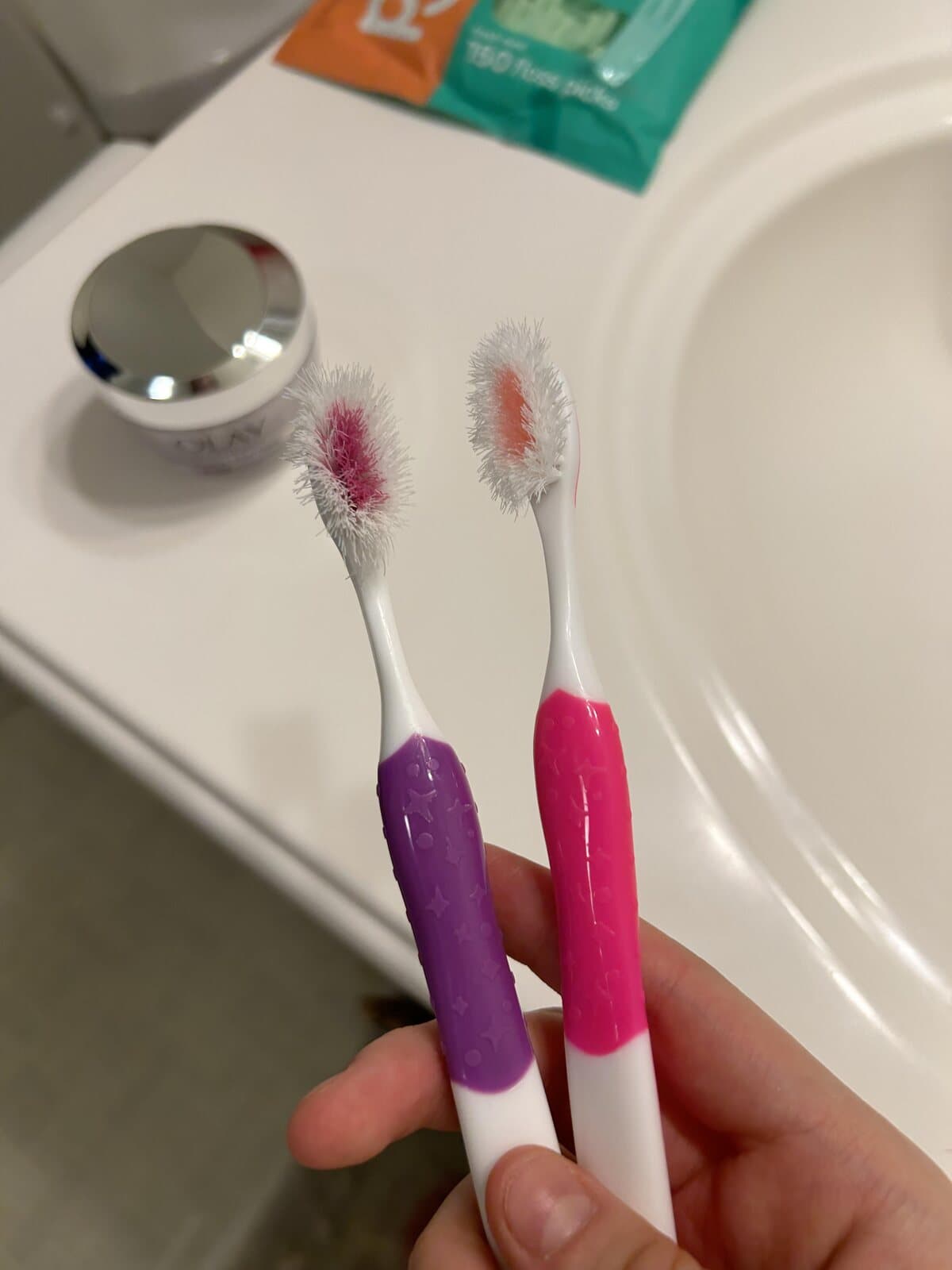 Two worn plastic toothbrushes with frayed nylon bristles